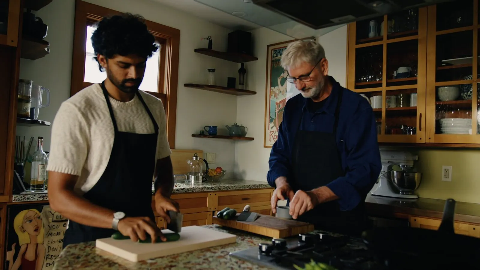 Akshay Prabhu and a home cook chop cucumber side by side during a private cooking lesson in a home kitchen