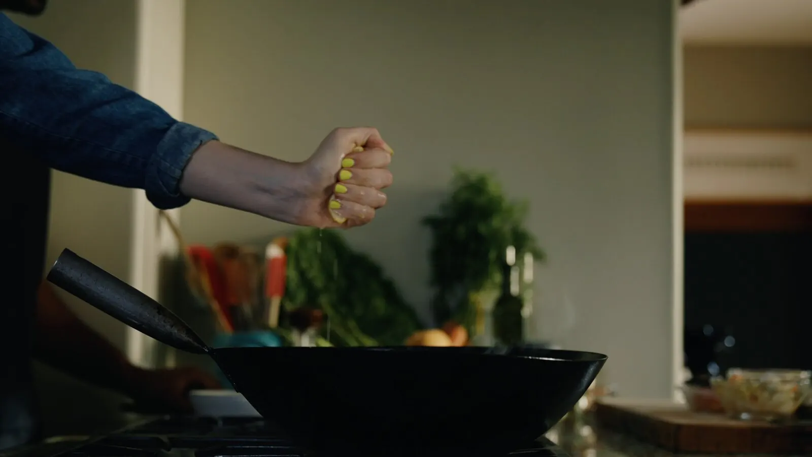 A hand squeezes lemon over a wok to finish a dish before tasting